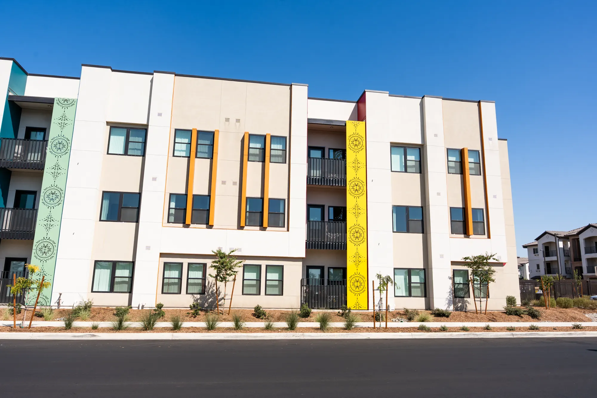Three-story Rancho Colegio building painted cream with yellow and green accent panels