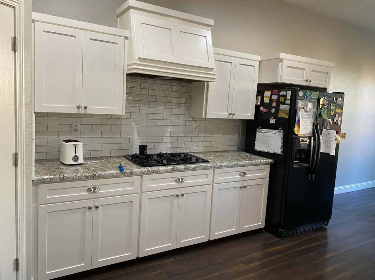 Freshly refinished white kitchen cabinets with brushed metal hardware
