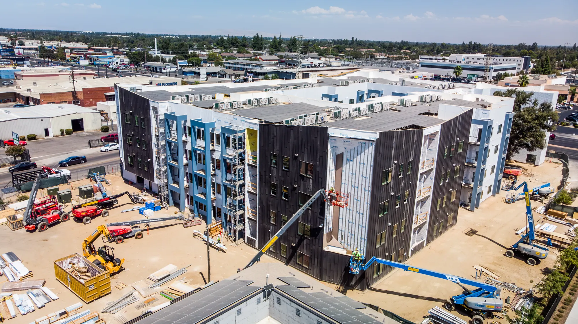 Aerial view of the Dakota housing development with boom lifts staged for exterior painting
